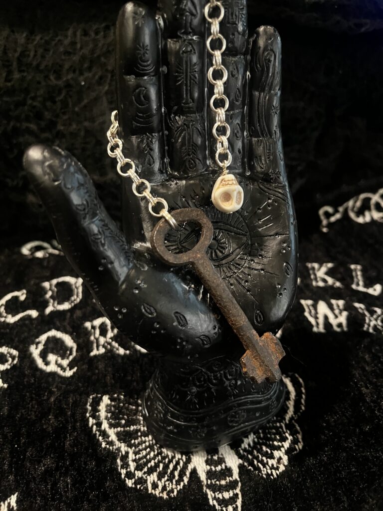 Skeleton key pendulum displayed on palmistry hand with ouija background